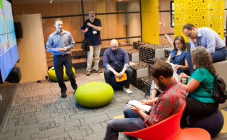 Several people try out a variety of seating options in a colorful workshop space
