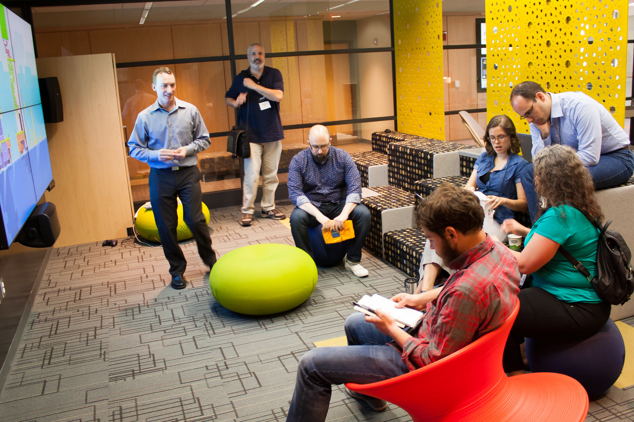 Several people try out a variety of seating options in a colorful workshop space