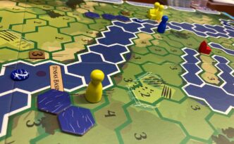 Close-up of the Rising Waters game board mid-play, with hexagons representing land and waters as well as brightly colored player pawns